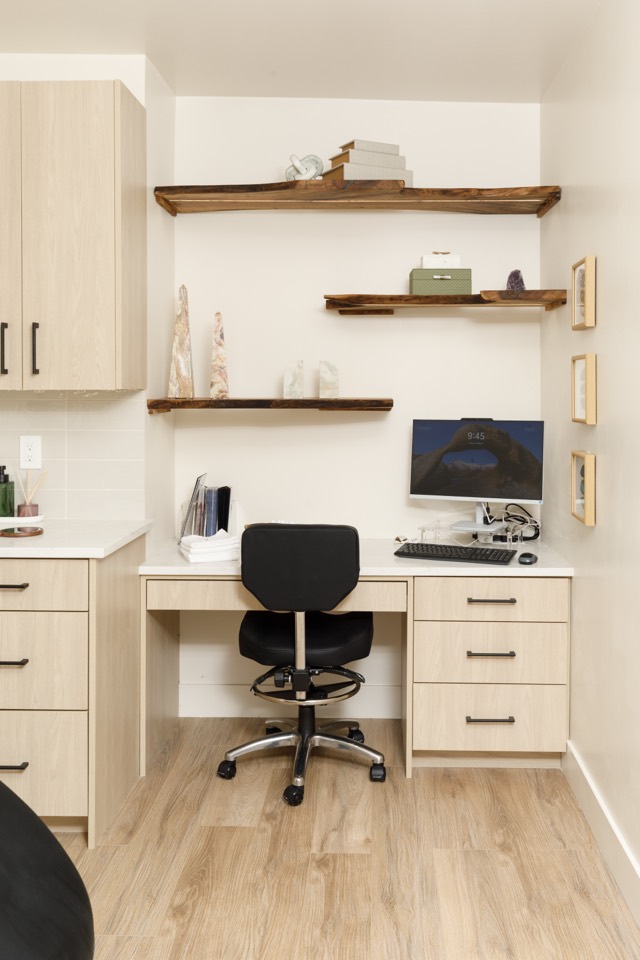 A desk nook with live edge wood shelves, a computer, and stone decor