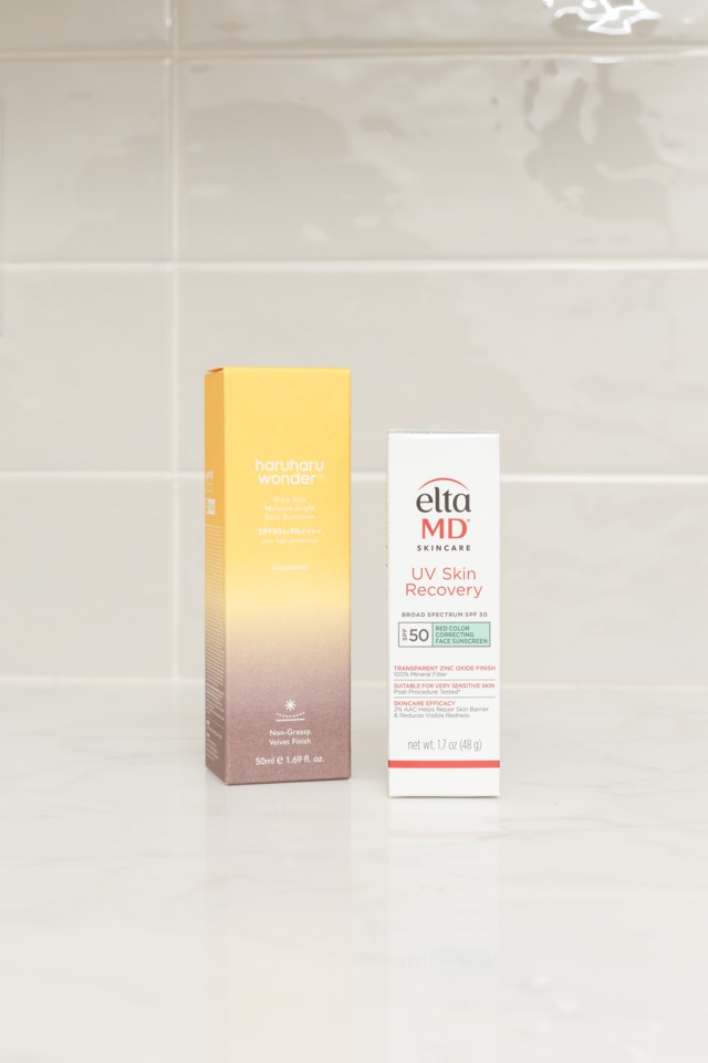 Two boxes of sunscreen standing on a white marble counter