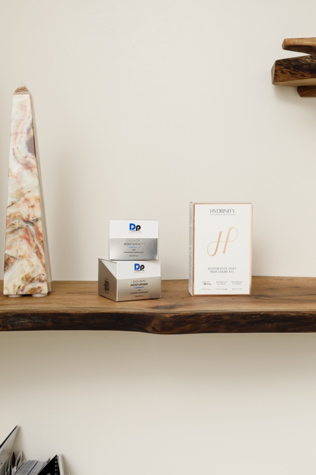 Skincare products on a live edge wood shelf beside a polished stone obelisk