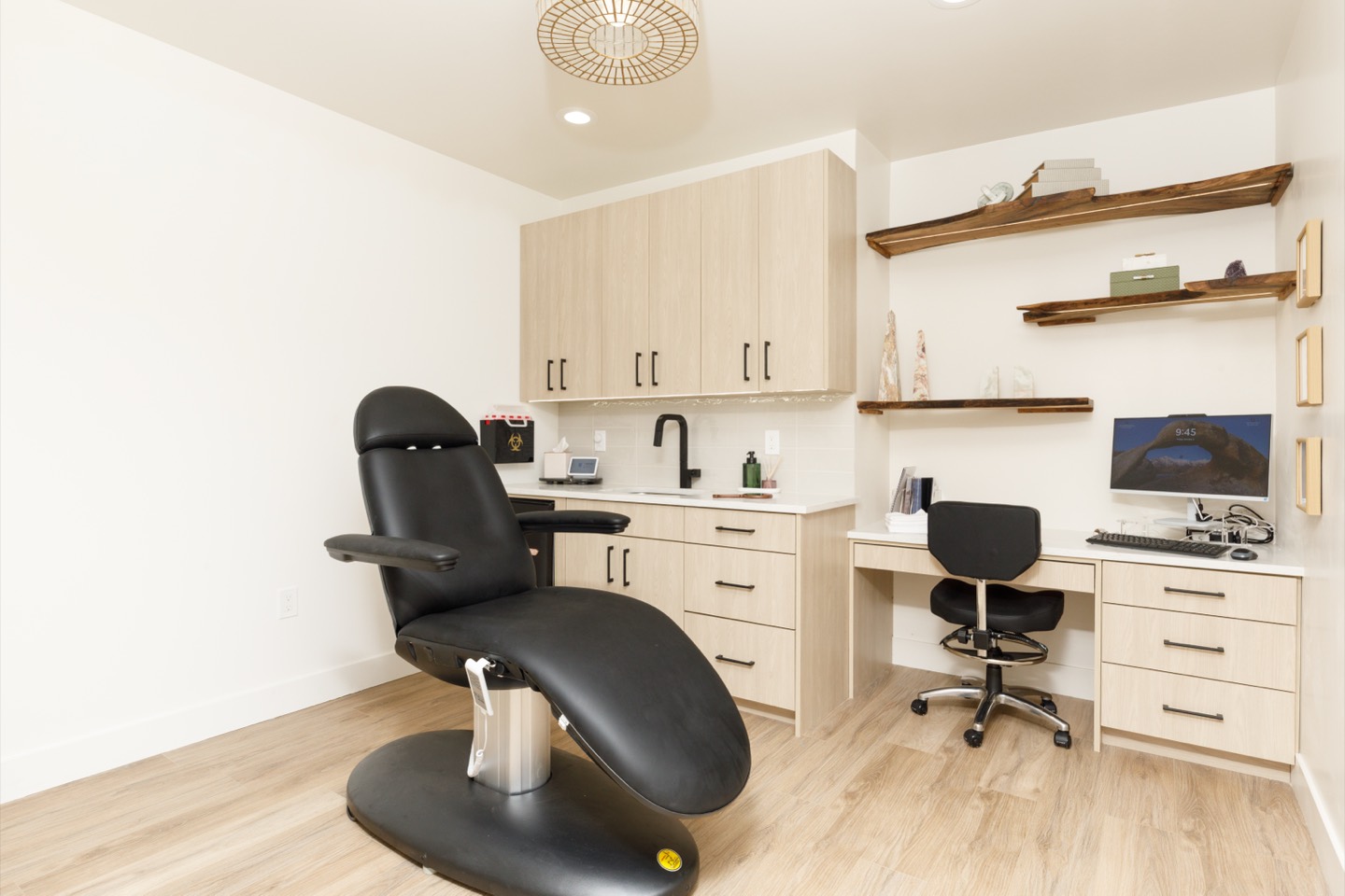 A wide view of the treatment room with chair, cabinetry, and desk